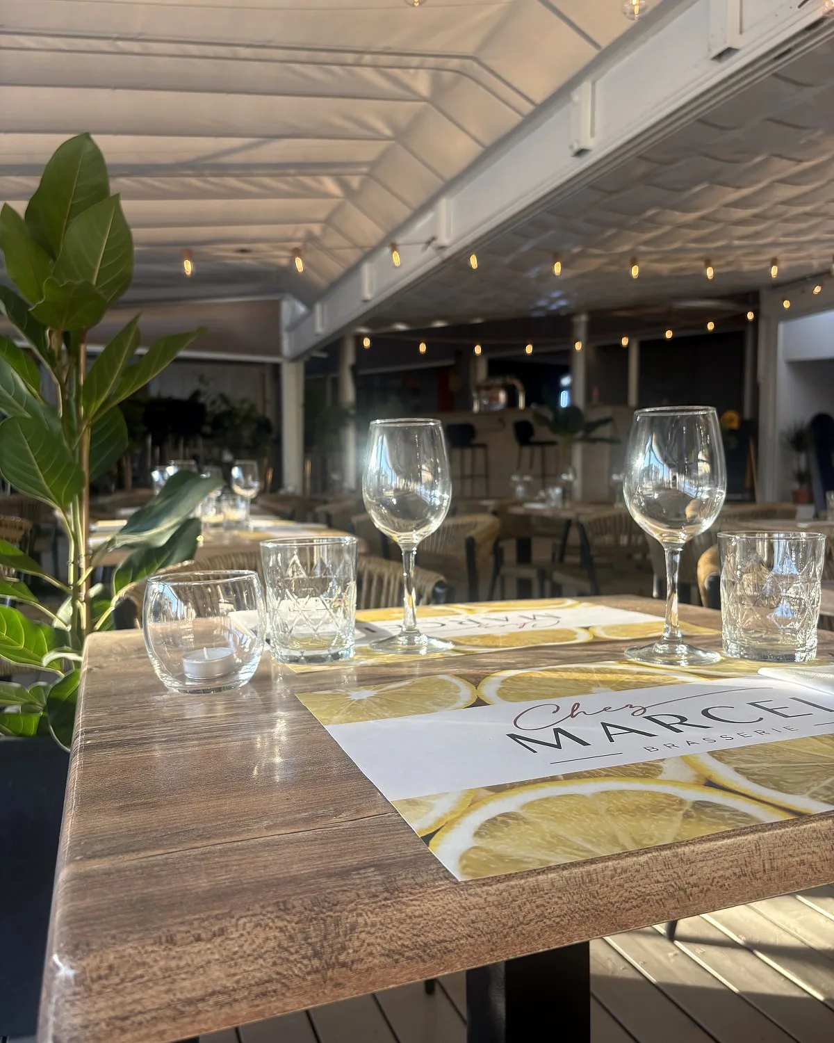 Table dressée en terrasse avec le set de table Chez Marcel Brasserie et ses verres à vin